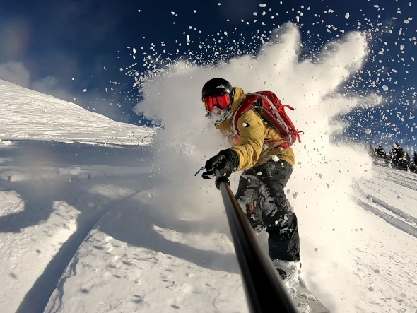 Ein Snowboarder, der durch eine Schneewolke fährt.